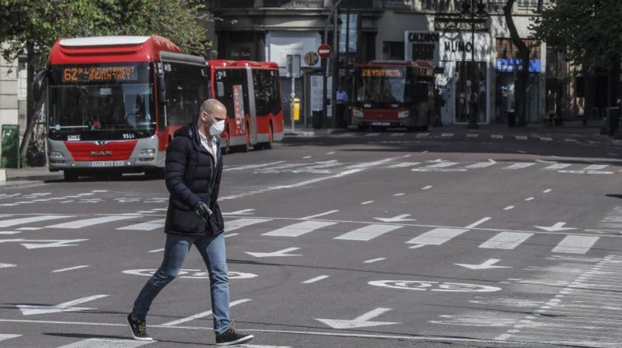 Un peatón camina junto a dos autobuses urbanos de Valencia