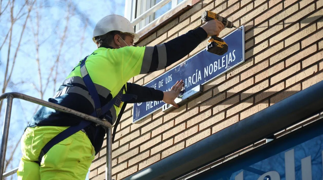 Un operario coloca de nuevo la placa de los Hermanos García Noblejas en Ciudad Lineal