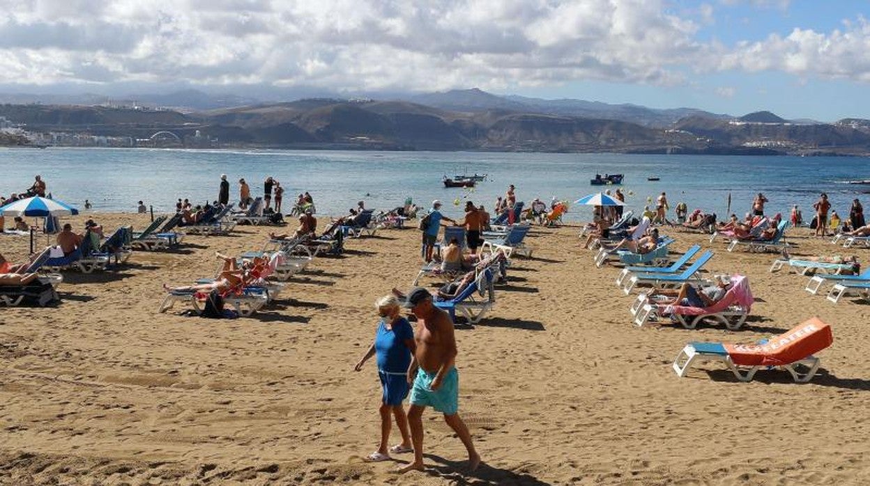 Turistas con mascarilla salen de la playa de Las Canteras, Gran Canaria