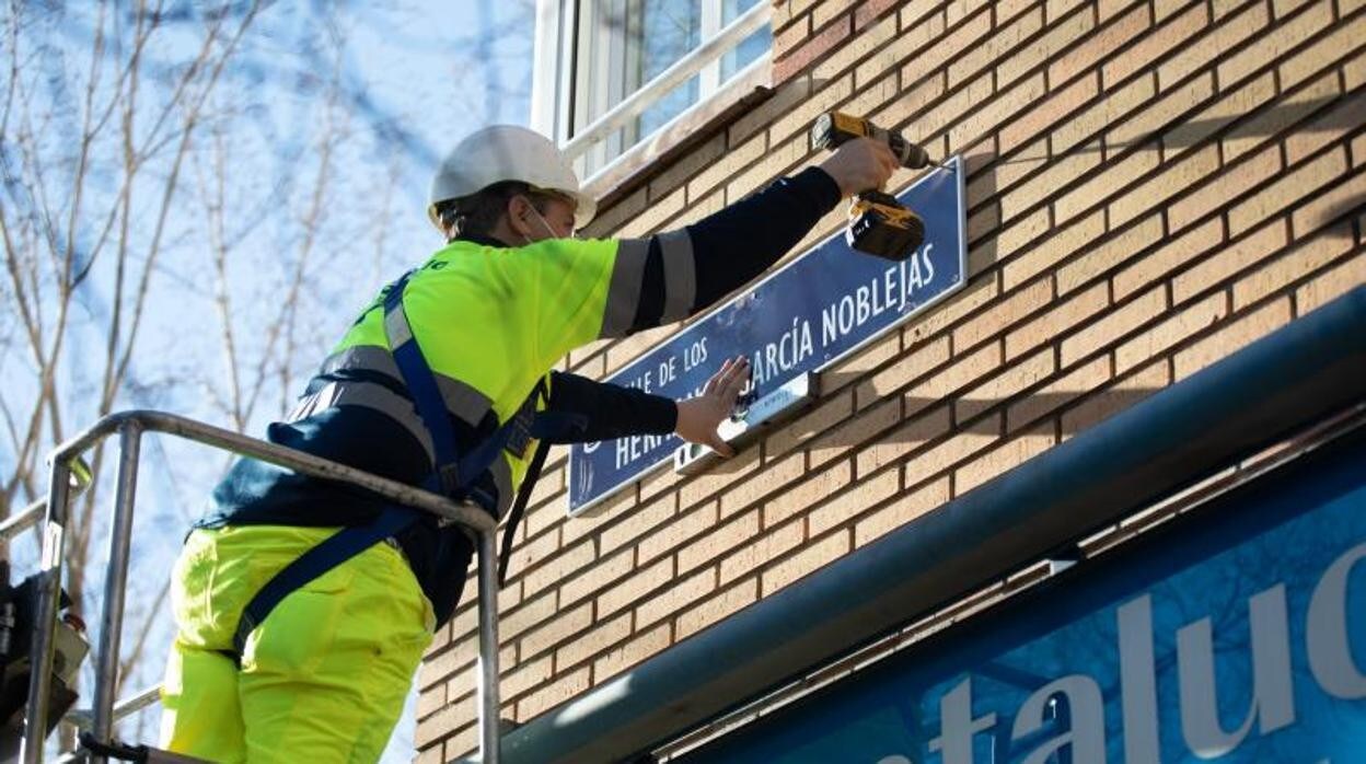 Un operario municipal repone la placa a los hermanos García Noblejas en el cruce con la calle de Alcalá