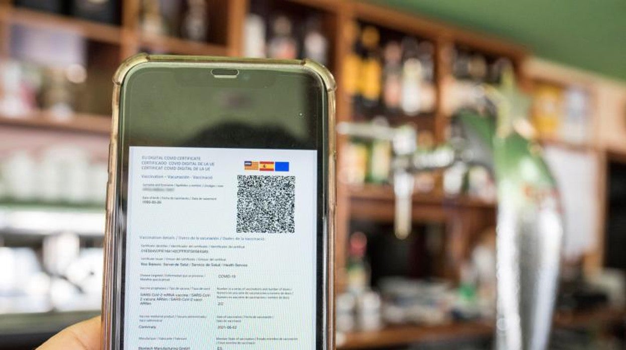 Detalle de un certificado Covid en un smartphone, en una cafetería