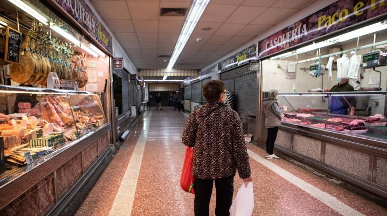 Varios clientes compran en el mercado de Numancia, en Puente de Vallecas, que cuenta con varios locales cerrados