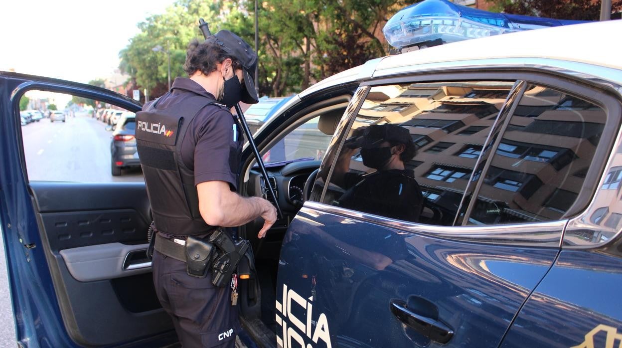 Un agente de la Policía Nacional sube a un coche patrulla