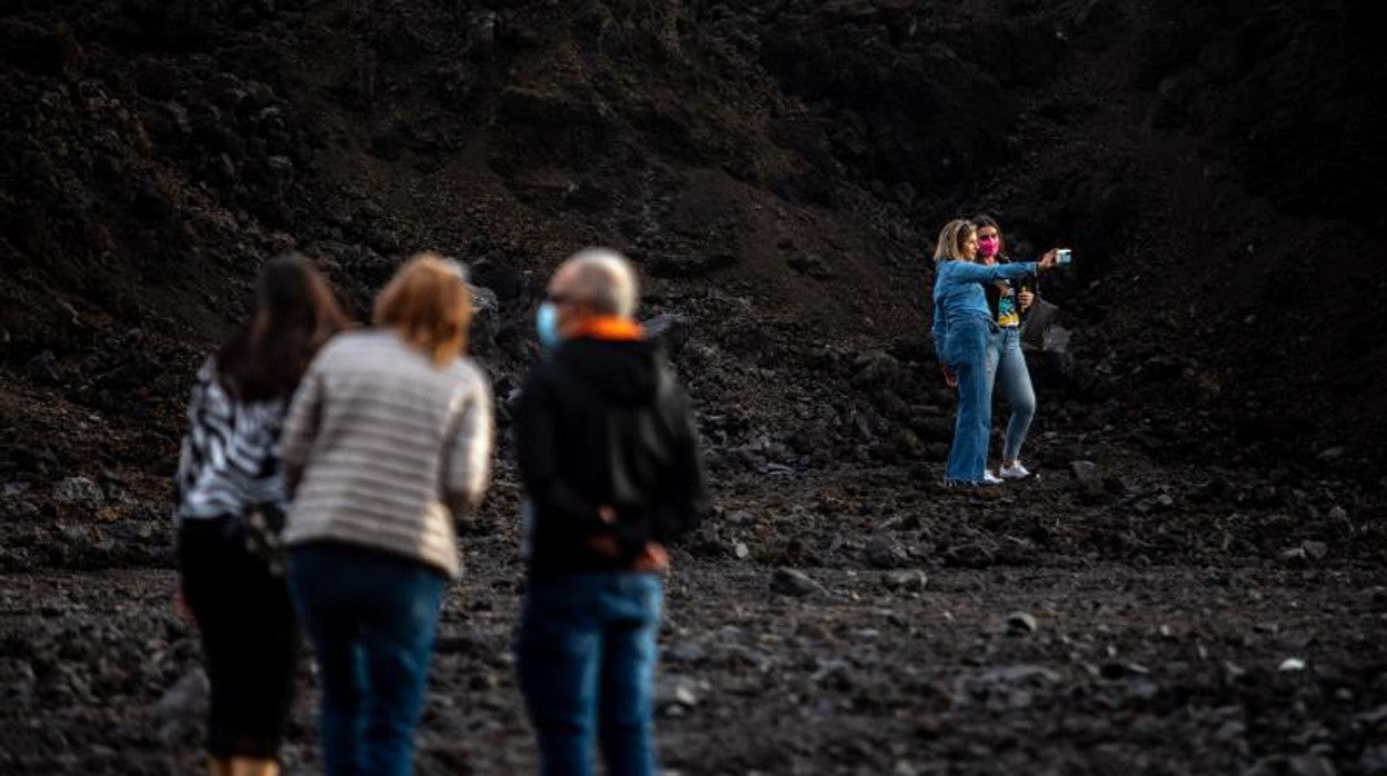 Una pareja de turistas se hacen un 'selfie' sobre la colada de lava del volcán de Cumbre Vieja