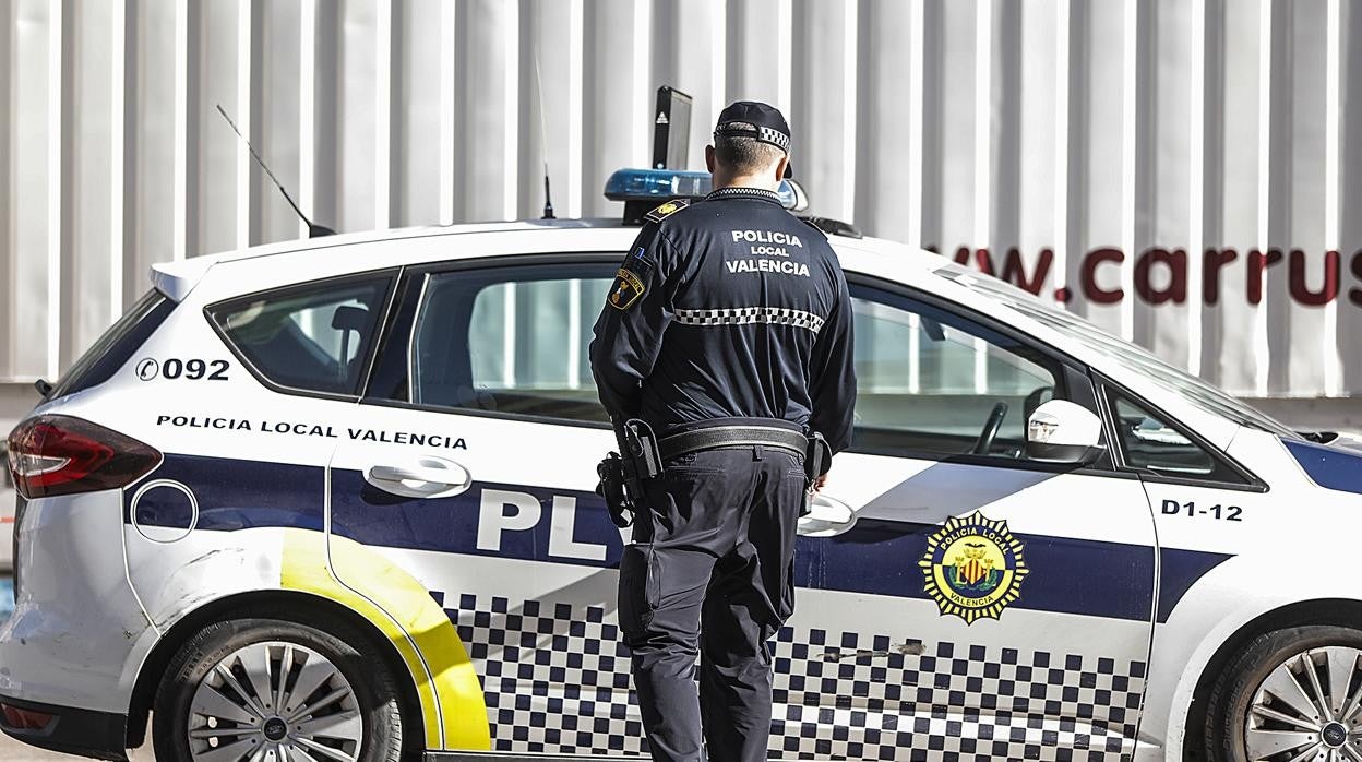 Imagen de recurso de un agente de la Policía Local de Valencia junto a su coche patrulla