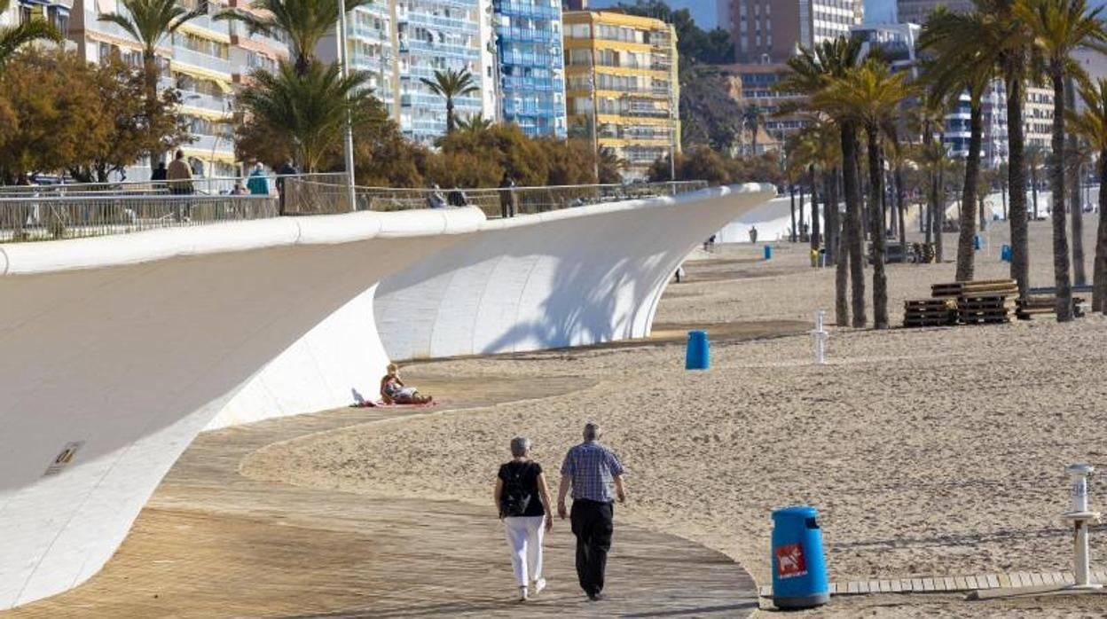 Una pareja de mayores pasea por la playa en Benidorm