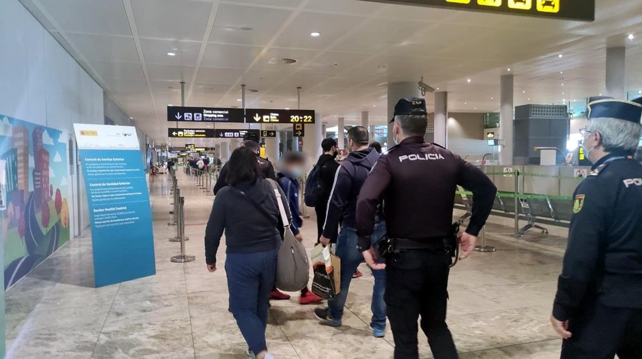 Agentes de la Policía Nacional junto a viajeros en el aeropuerto de Alicante-Elche