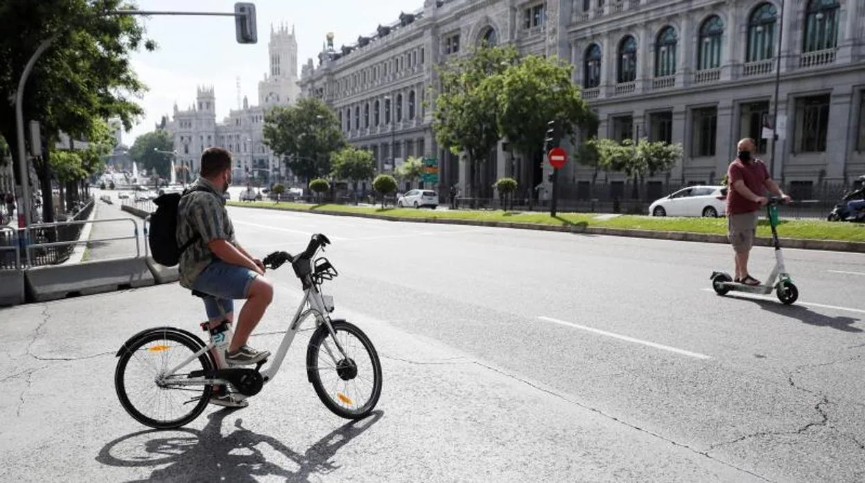 Un hombre transita la calle de Alcalá con una bicicleta Bicimad