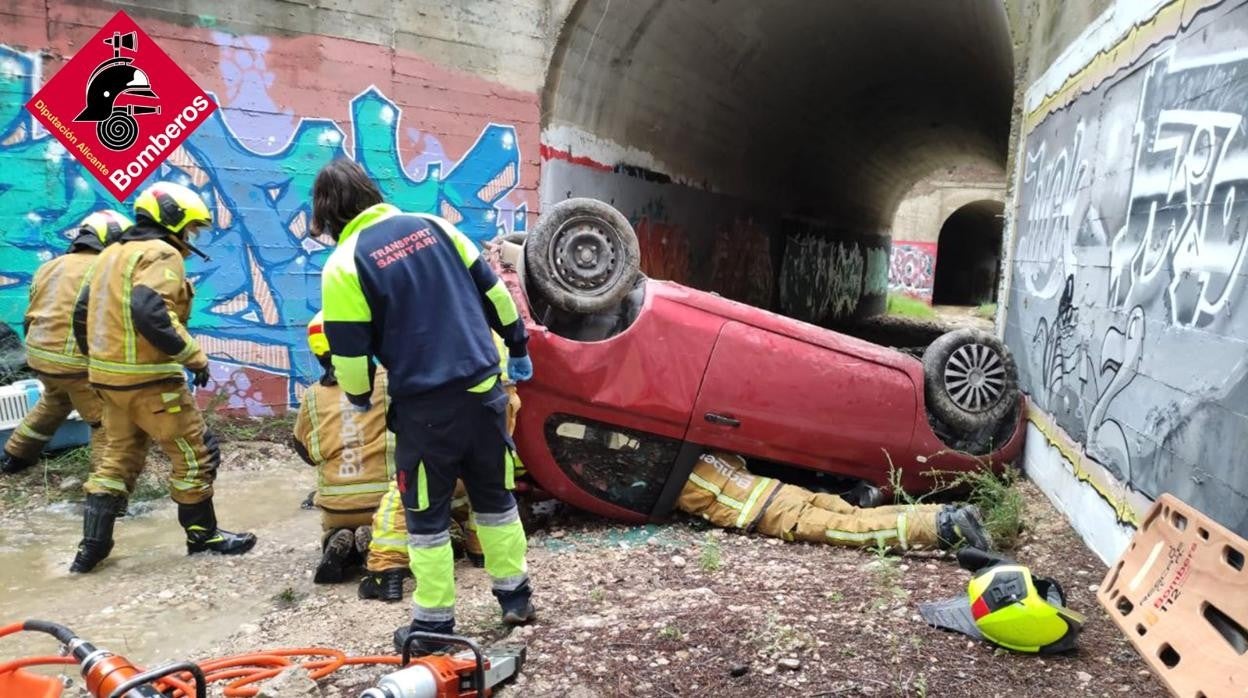 Bomberos durante el rescate de la conductora, atrapada en su coche boca abajo