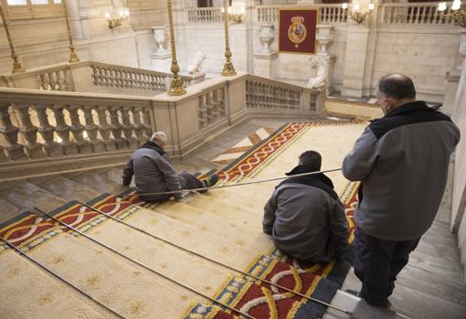 El equipo de cerrajeros retira las varillas que fijan la alfombra a la escalera de piedra