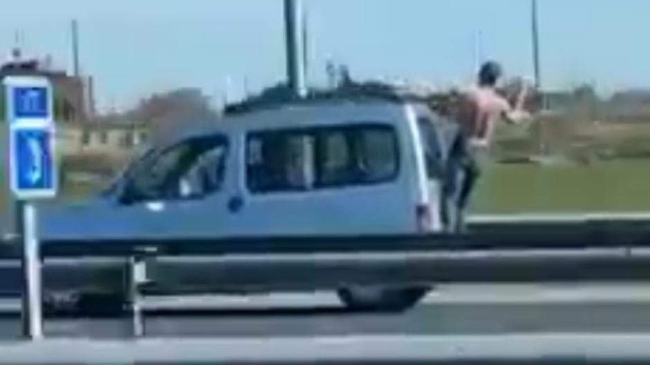 Riesgo extremo en la A-5: un hombre con el torso desnudo se encarama a una furgoneta sujeto solo por las manos