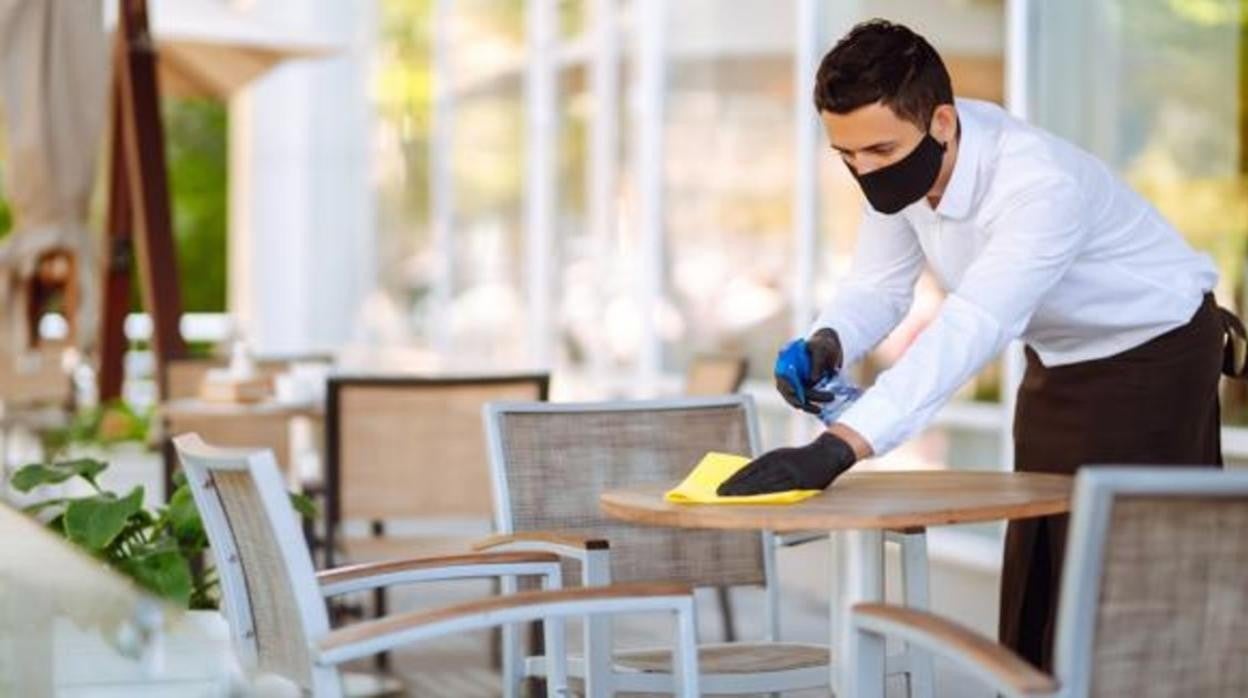 Un camarero limpia una mesa de una terraza