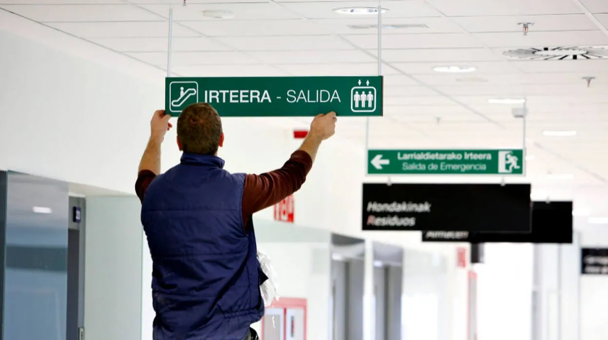 Un operario coloca un cartel bilingüe en un lugar público
