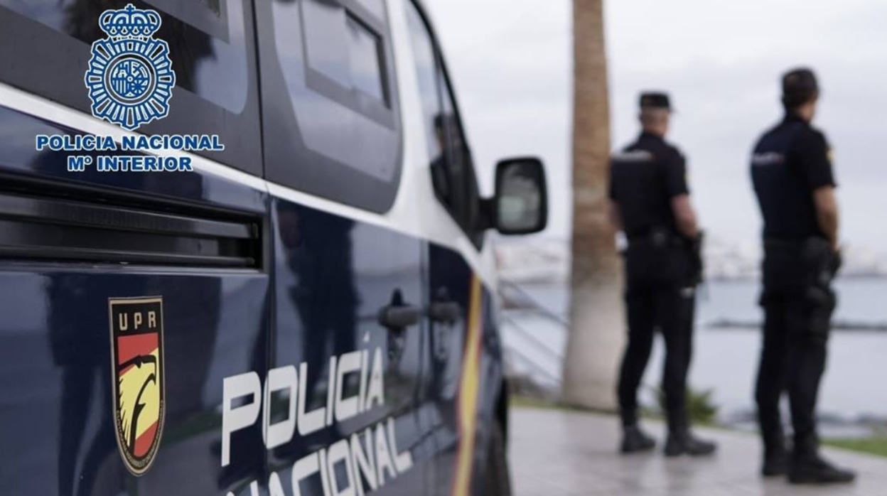 Dos agentes y el vehículo patrulla de la Policía Nacional en foto de archivo