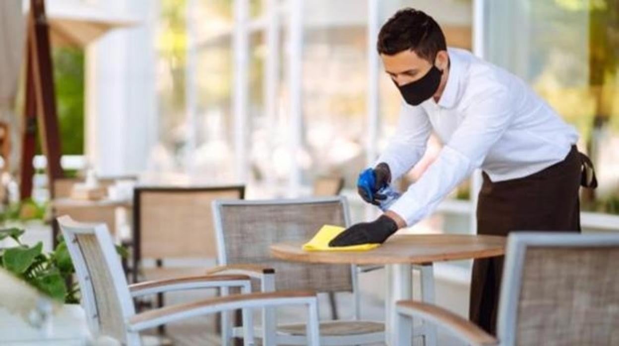 Un camarero limpia la mesa de una terraza