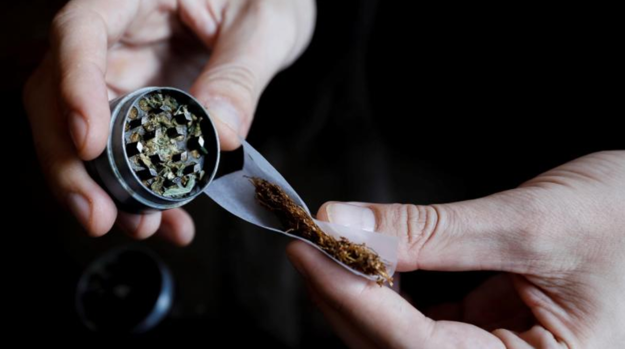 Una persona se lía un cigarro con marihuana en foto de archivo.