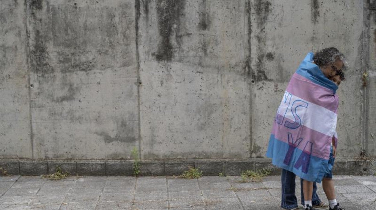 María José Rodríguez abraza a su hijo Alejandro, envueltos en la bandera trans