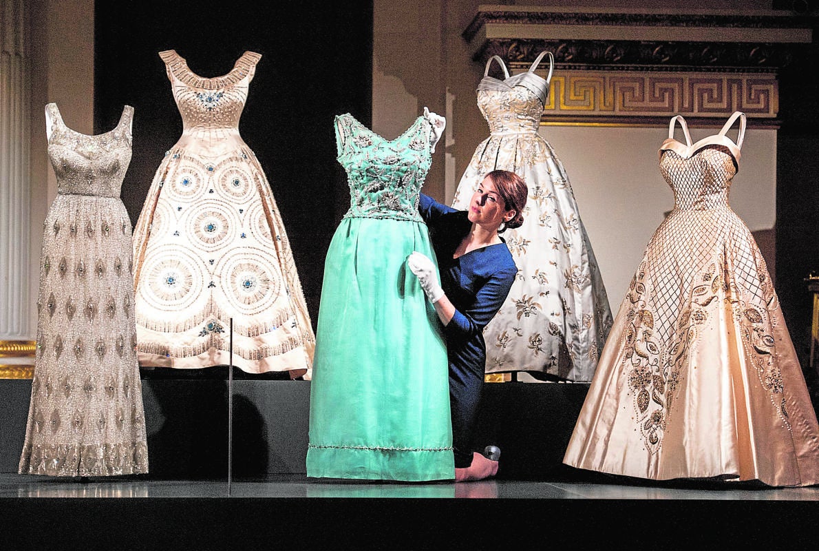 Una empleada da los últimos retoques a uno de los vestidos expuestos en el Palacio de Buckingham