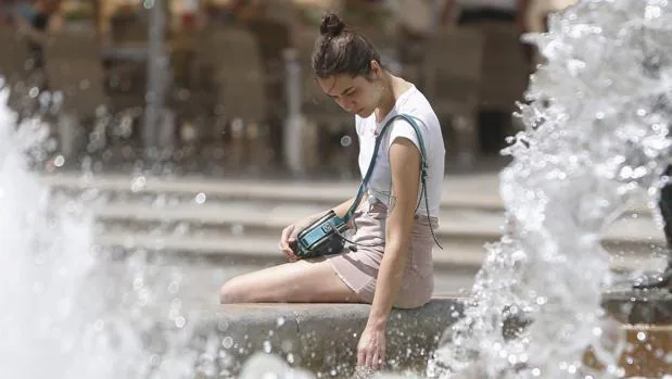 Una joven se refresca en una fuente de Valencia