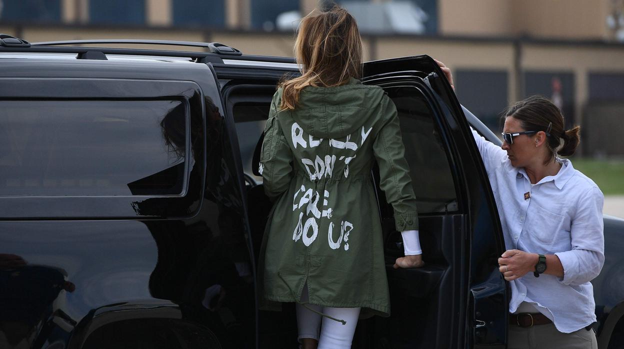 Melania Trump de espaldas -donde se lee el mensaje- subiendo al coche