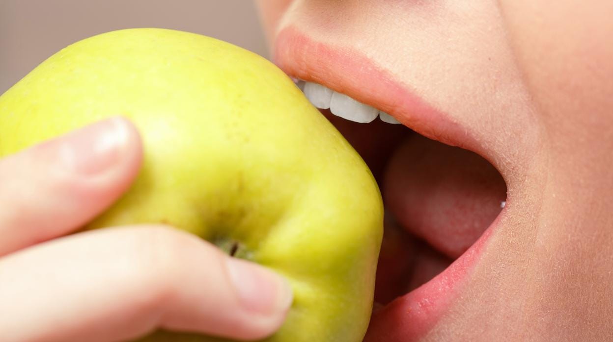 Una mujer, mordiendo una manzana.