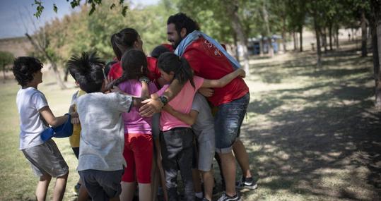 Un monitor y algunos niños se abrazan después de una de las actividades