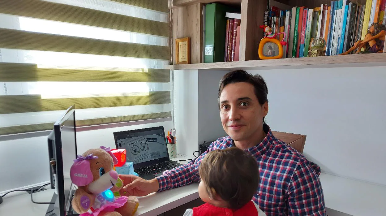 Javier con su pequeña de un año en su despacho de trabajo en casa