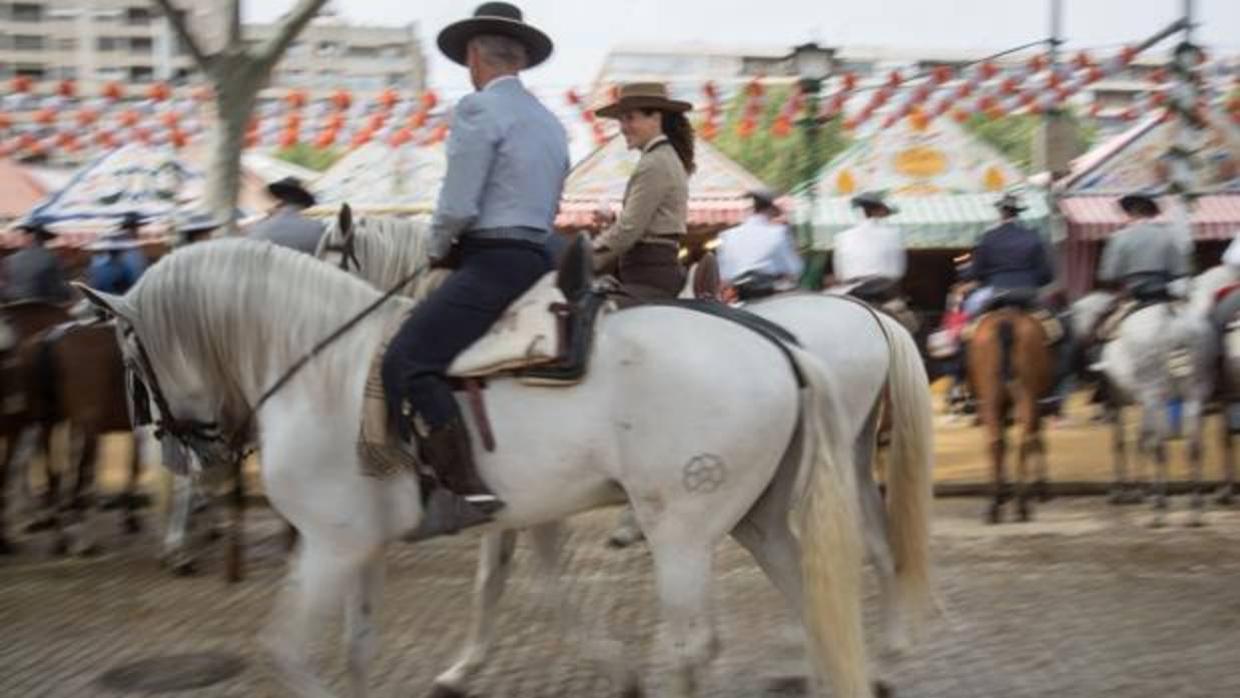 Varios caballistas pasean por el recinto ferial