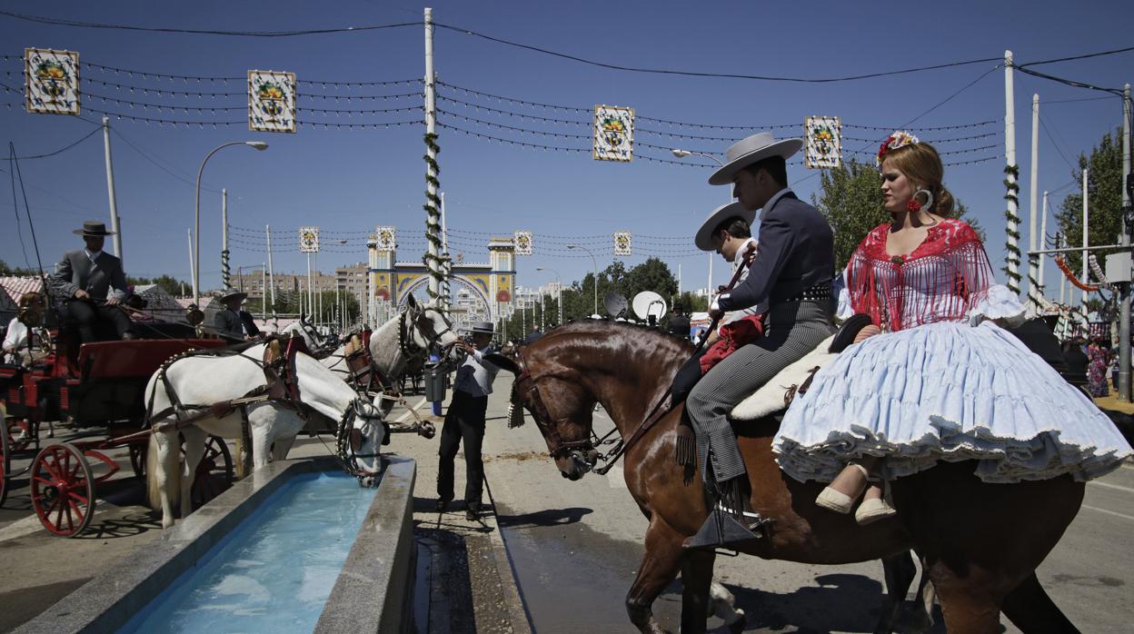 Un caballista lleva a su caballo a beber agua durante la Feria de Abril