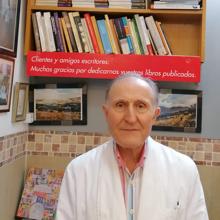 Miguel posa ante la estantería que luce todos los libros escritos y dedicados por los clientes que han pasado por El Bierzo