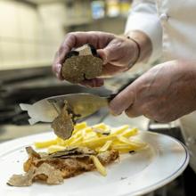 María Luisa laminando trufa de verano sobre uno de sus platos de huevos fritos con patatas