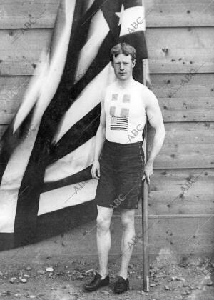 El atleta norteamericano Thomas Pelham Curtis posa junto a la bandera de su país...