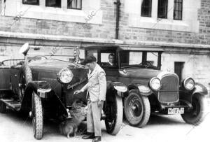 El infante Juan de Borbón juega con su perro delante de un automóvil Hispano...