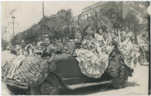 Un automóvil lleno de mujeres vestidas de flamenca las calles y el Real