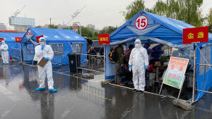 Pertrechados con traje de protección, funcionarios de Pekín controlan a viajeros...