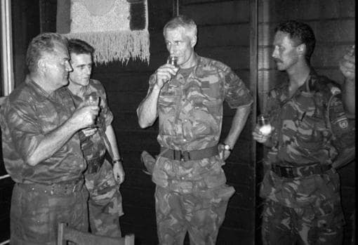 El comandante del ejército serbio de Bosnia, general Ratko Mladic, a la izquierda, sostiene un vaso después de brindar con el comandante holandés U.N. Thomas Karremans, en el centro