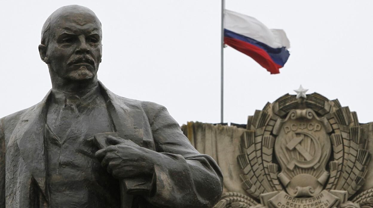Una estatua de Lenin frente a una bandera rusa, en 2017