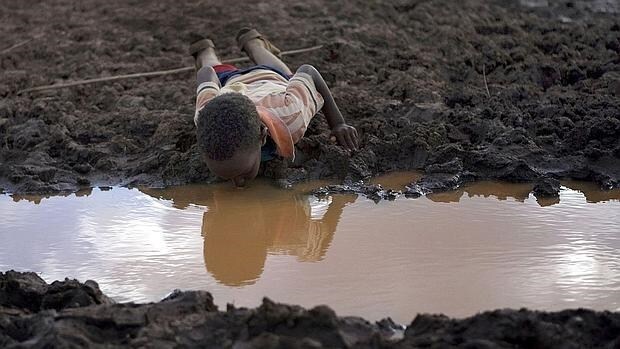 Un niño bebe agua en un charco de la aldea etíope de Bule Duba