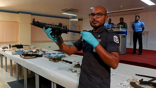 Un policía muestra una de las armas encontradas durante la investigación del atentado contra el presidente