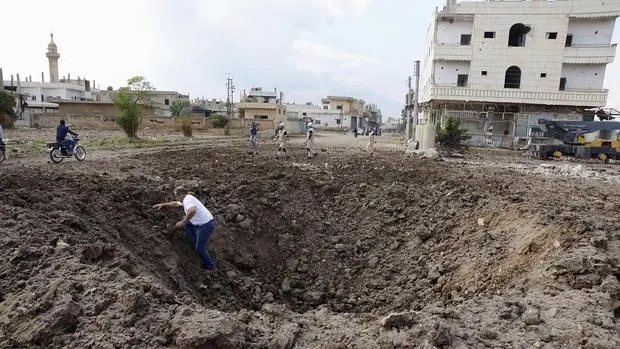 Un hombre sale de un agujero causado por una bomba lanzada por fuerzas afines a Al Assad