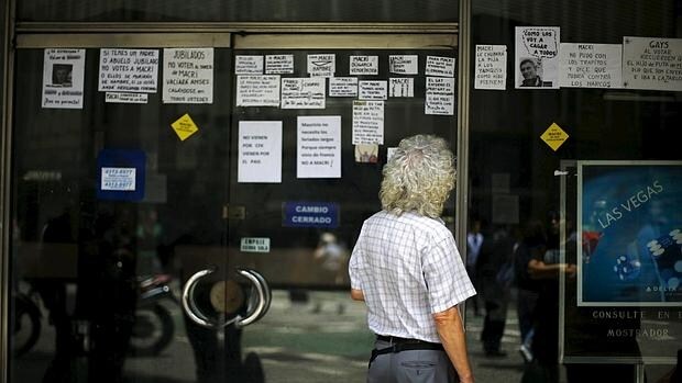 Un hombre lee mensaje contra Macri en una tienda de cambio cerrado en Buenos Aires
