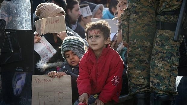 Varios niños refugiados muestran carteles pidiendo ayuda