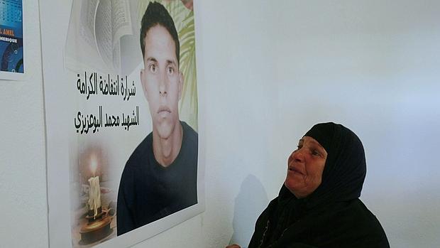 La madre de Bouazizi ante un retrato del joven, que se inmoló hace cinco años