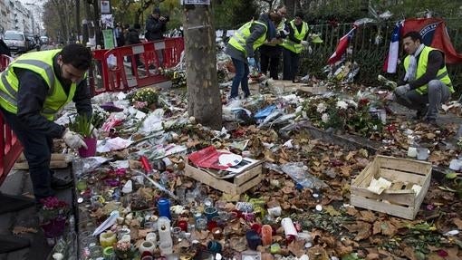 Empleados municipales retiran las flores y velas colocadas en memoria de las víctimas ante la sala Bataclán