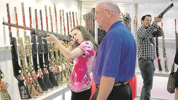 Unos norteamericanos revisan unos fusiles exhibidos por la Asociación Nacional del Rifle en Huston (Texas)