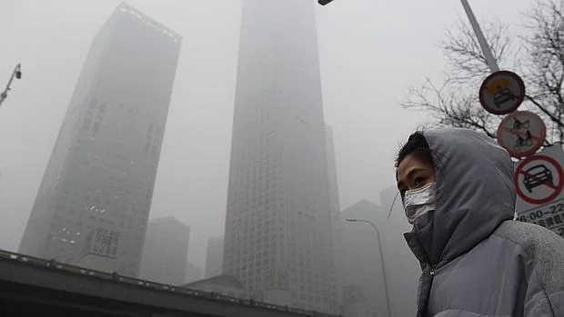 Una mujer camina por una calle de Pekín con una mascarilla