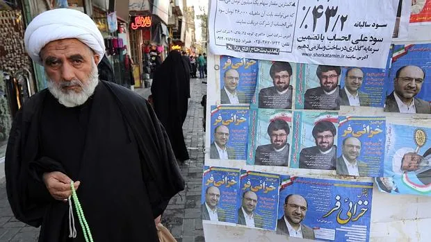 Un clérigo pasa ante un cartel electoral en la ciudad iraní de Qom