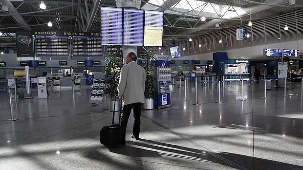 Un pasajero se detiene ante un panel informativo en el vestíbulo de facturación del aeropuerto ateniense Eleftherios Venizelos