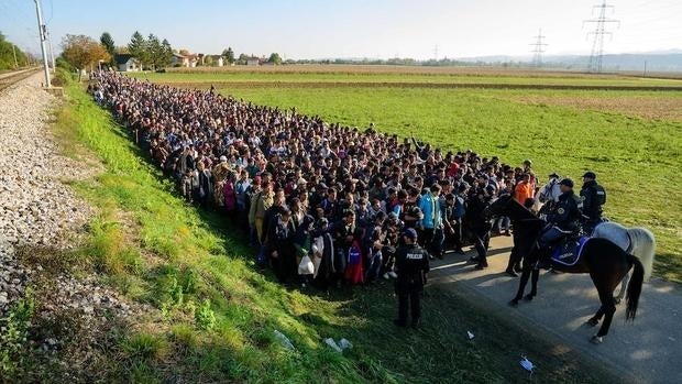 Un grupo de refugiados vigilados por la Policía en la frontera entre Croacia y Eslovenia