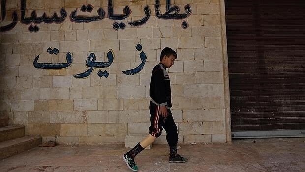 Un niño con una pierna amputada camina usando una prótesis en la zona rebelde Maaret al-Numan